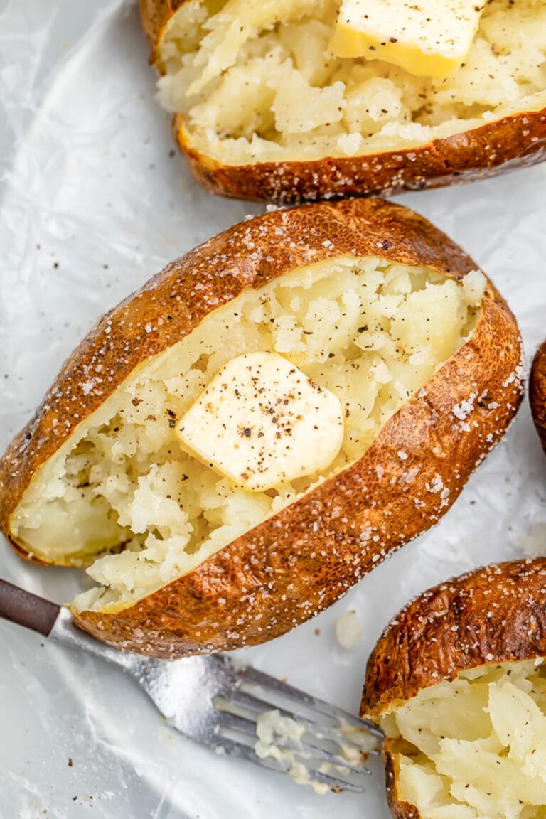 Air fryer baked potato crusted in salt, split in the middle and fluffed, then topped with butter and pepper.