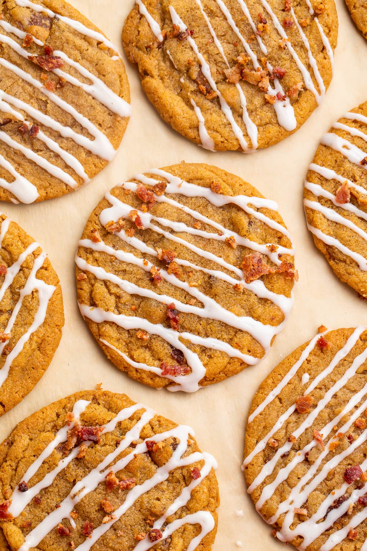 Bacon cookie butter cookies with a cinnamon glaze drizzle arranged on parchment paper.