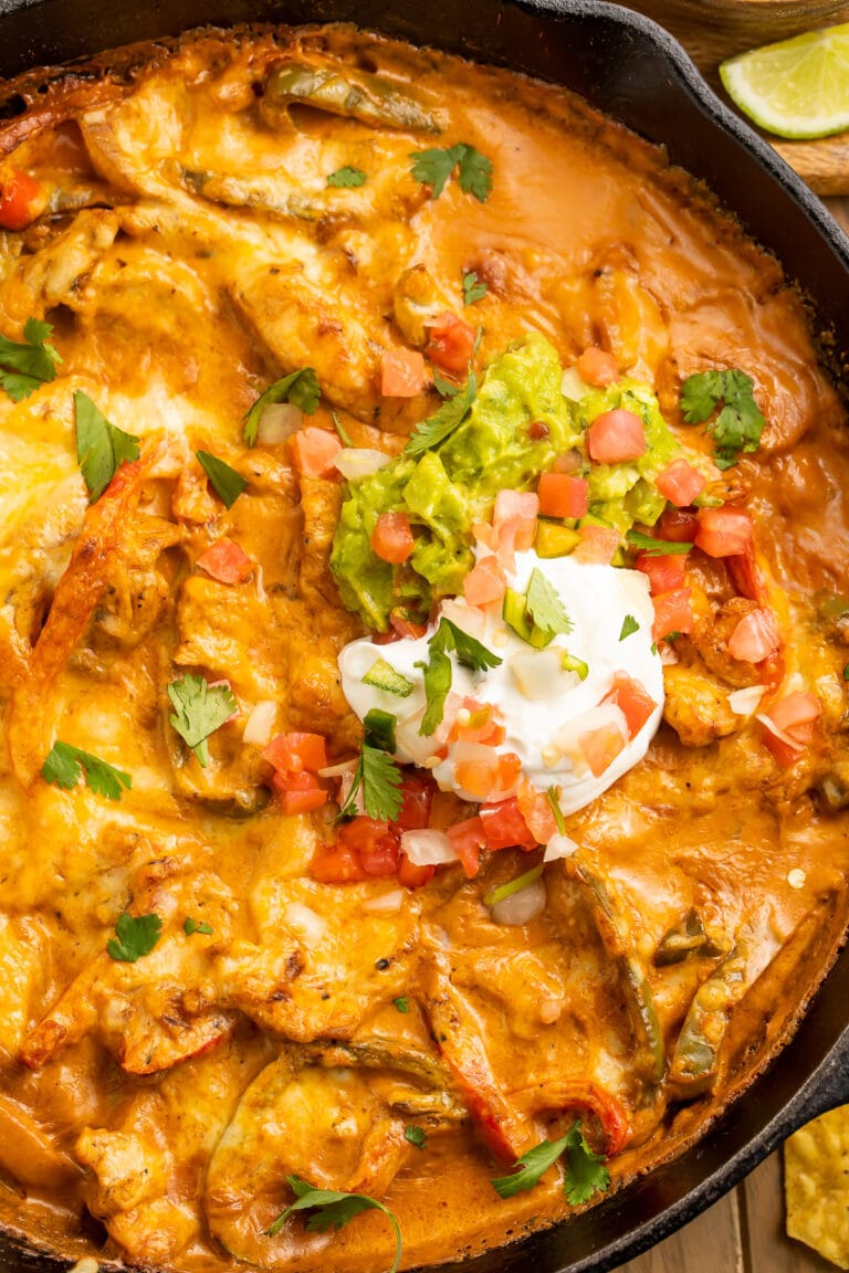 Chicken fajita casserole with a creamy sauce and a dollop of sour cream in a cast-iron skillet.