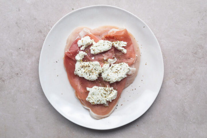 Prosciutto and goat cheese and Italian seasoning on a butterflied chicken breast.