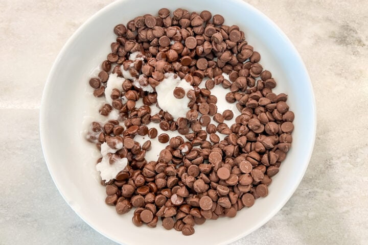 Keto chocolate chips and refined coconut oil in a medium mixing bowl.