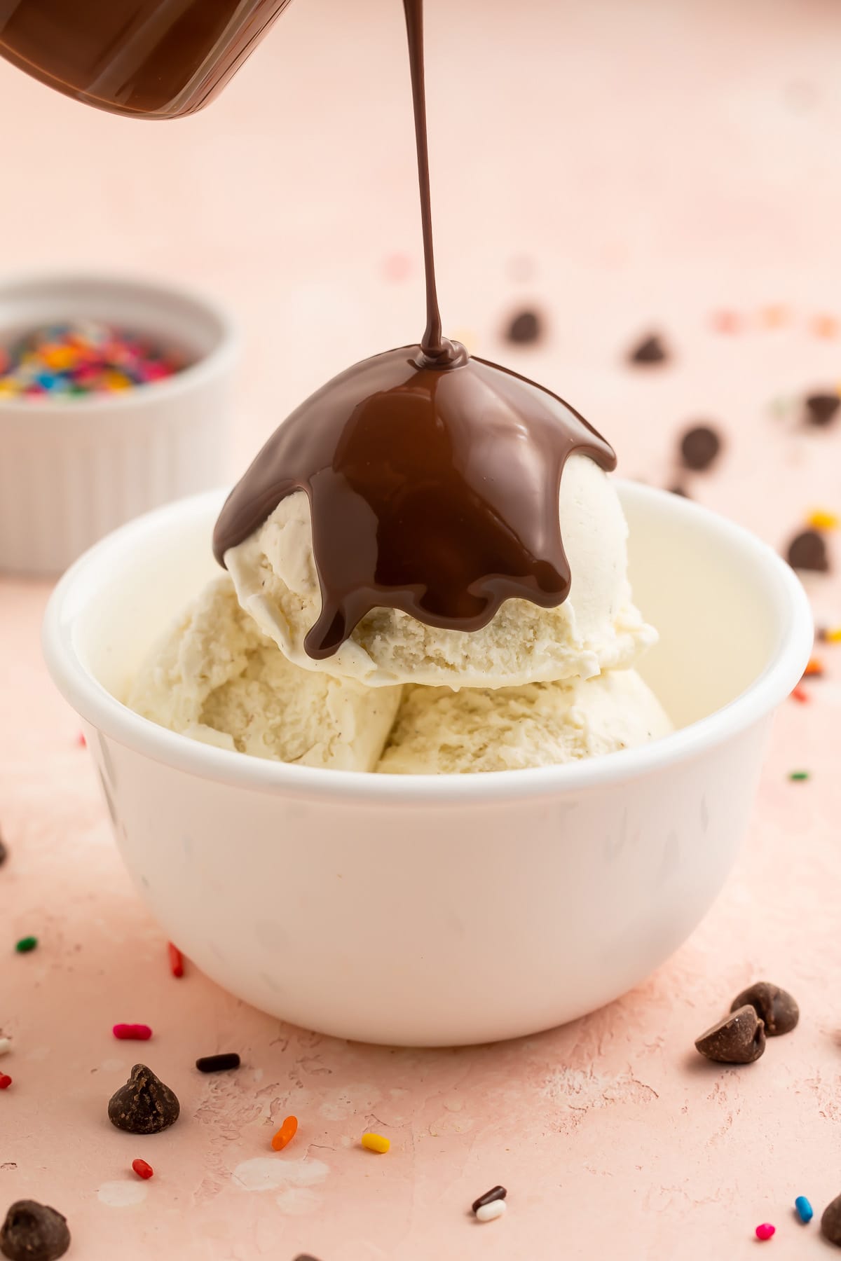 Chocolate keto magic shell being poured over a bowl of keto vanilla ice cream.