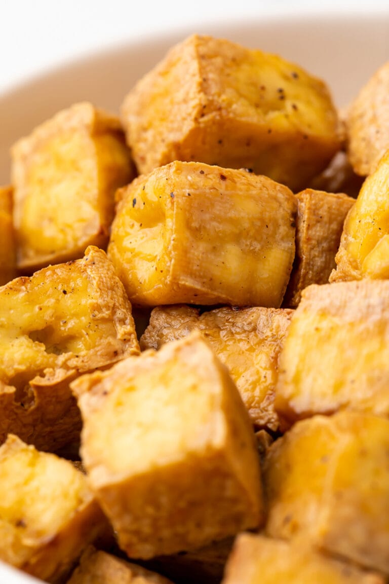 Cubes of crispy, marinated air fried tofu in a white bowl.