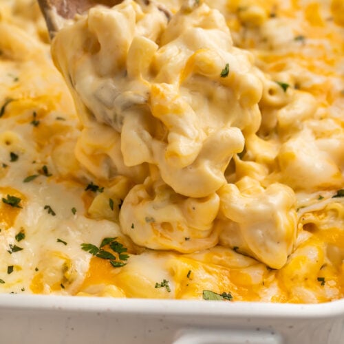 A spoonful of green chili mac and cheese being lifted out of a casserole dish.