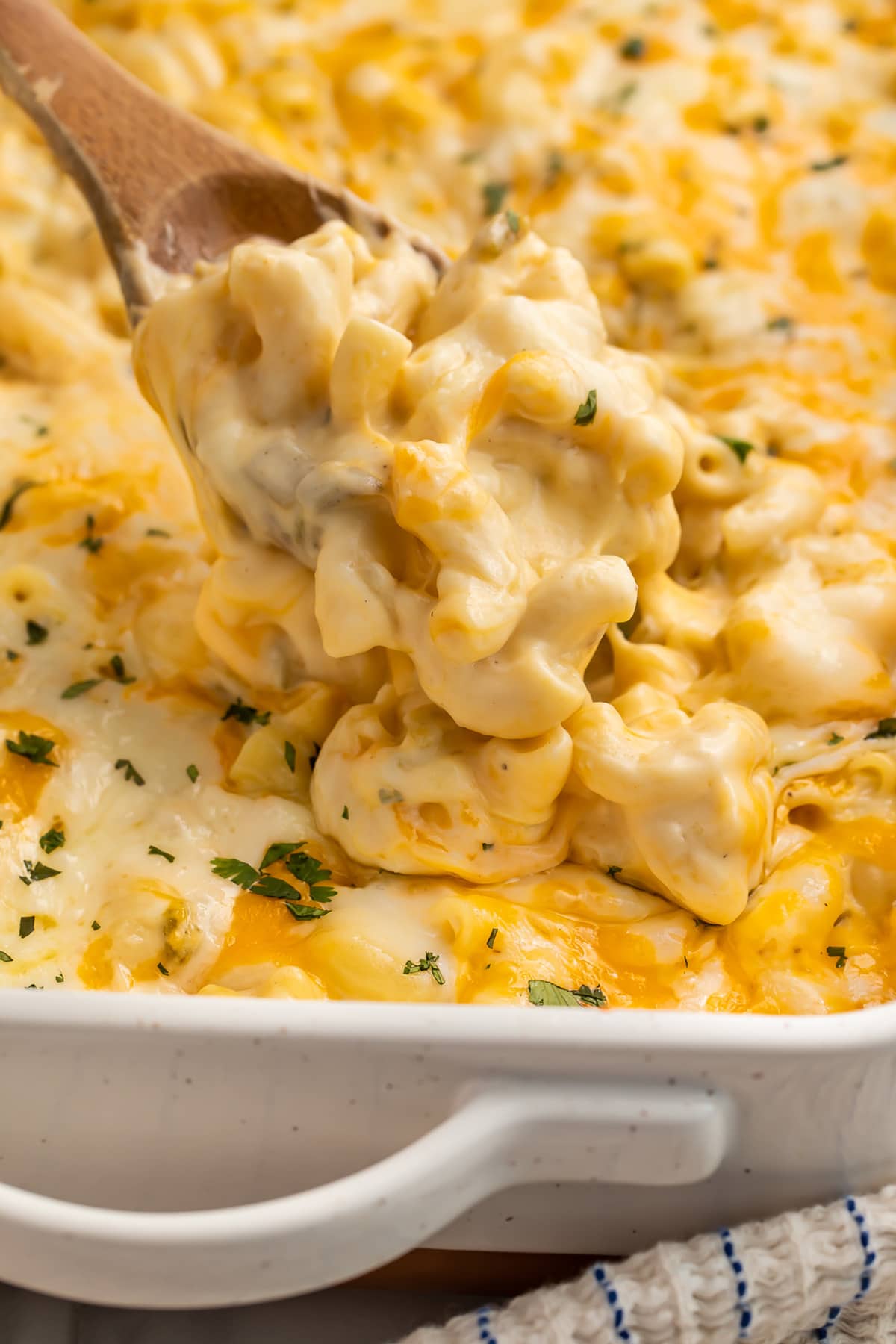 A spoonful of green chili mac and cheese being lifted out of a casserole dish.