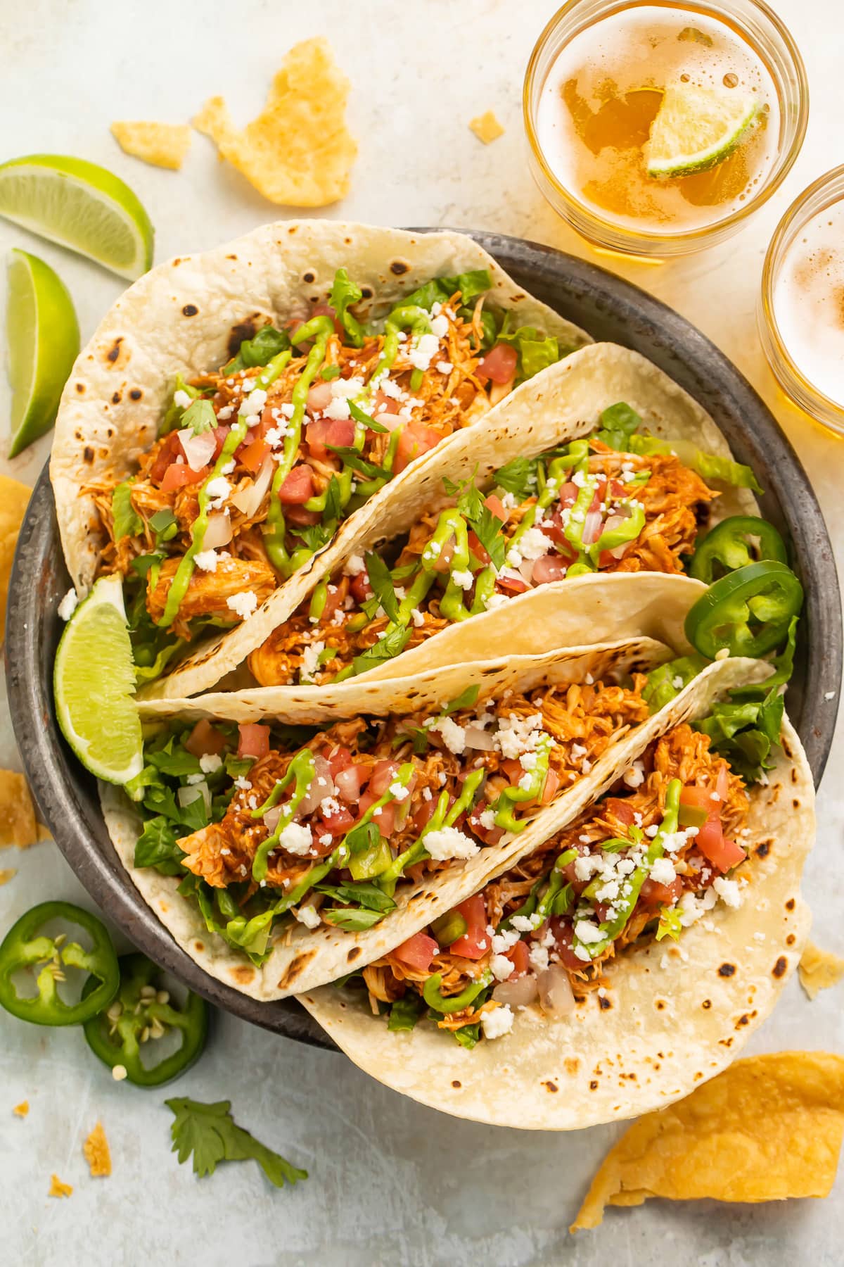 4 stuffed chicken tacos arranged on a plate. The tacos are filled with lettuce, tomato, cheese, and shredded chicken.