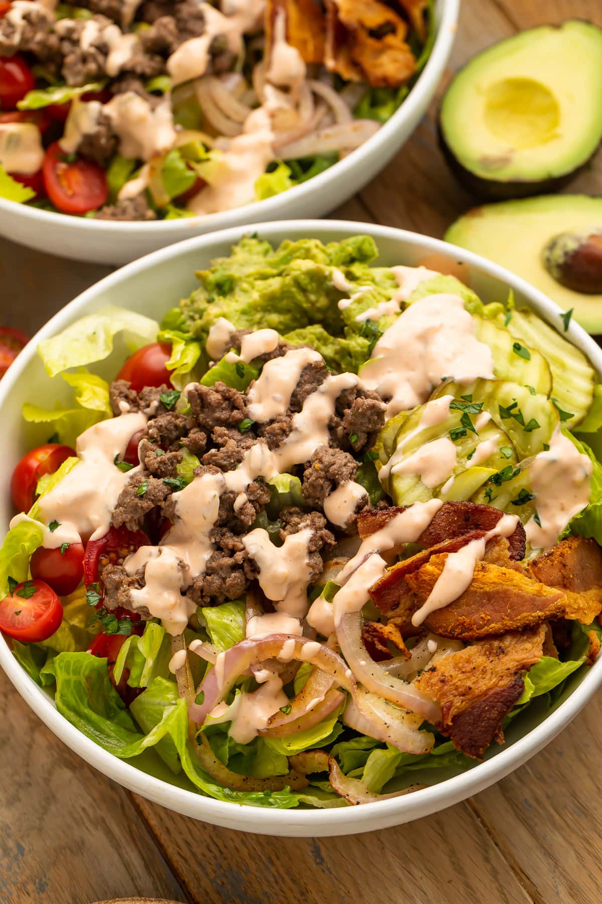 Angled view of a loaded burger bowl with pickles, onions, ground beef, and special sauce.