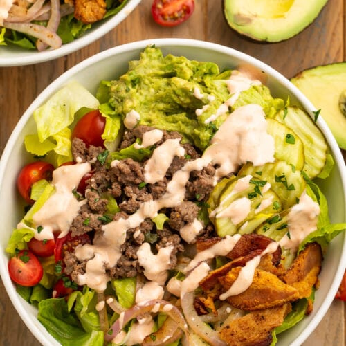 Top-down view of a loaded burger bowl with pickles, onions, ground beef, and special sauce.