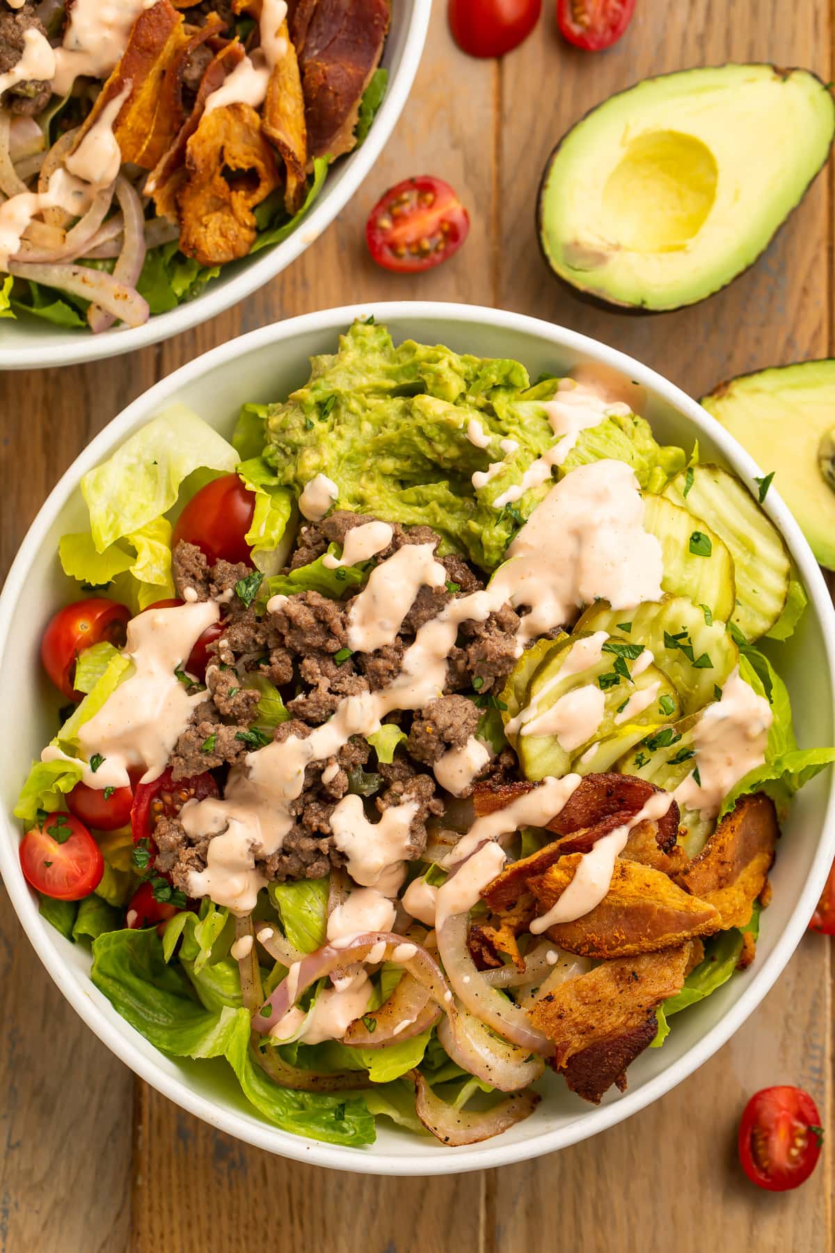 Top-down view of a loaded burger bowl with pickles, onions, ground beef, and special sauce.