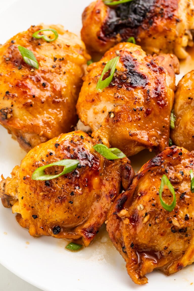 Instant Pot chicken adobo on a large white plate, garnished with sliced green onions.