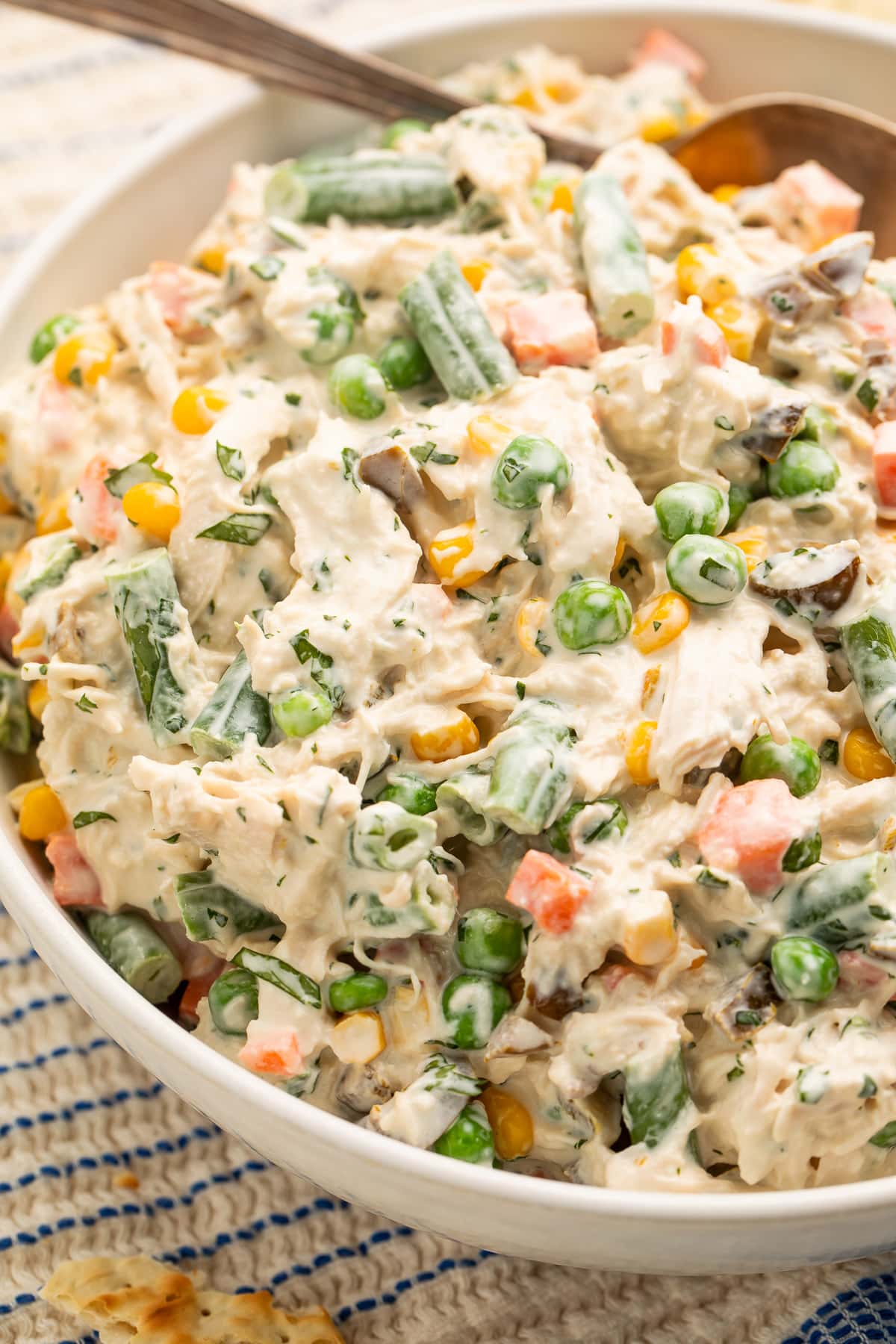 Side view of a large white bowl holding Mexican chicken salad made with shredded chicken, mixed vegetables, and sour cream.