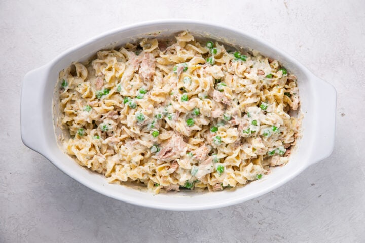 Unbaked tuna noodle casserole in a large white oval casserole dish.