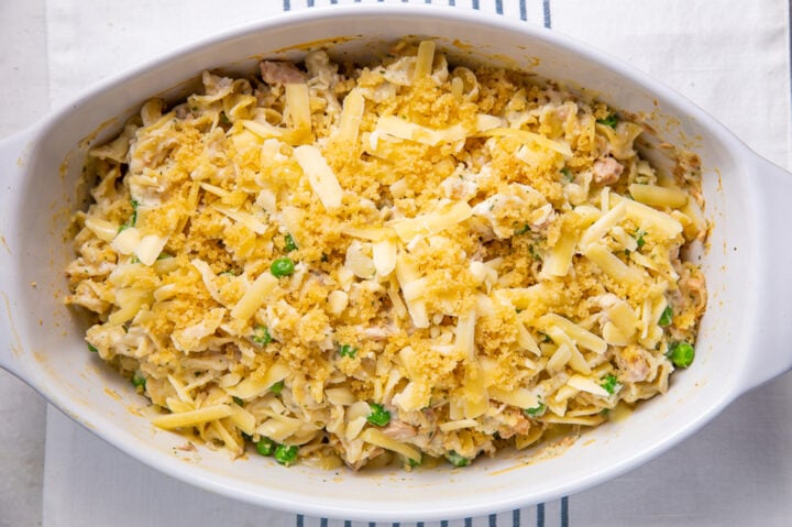 Prepared tuna noodle casserole garnished with chopped fresh parsley in an oval casserole dish.