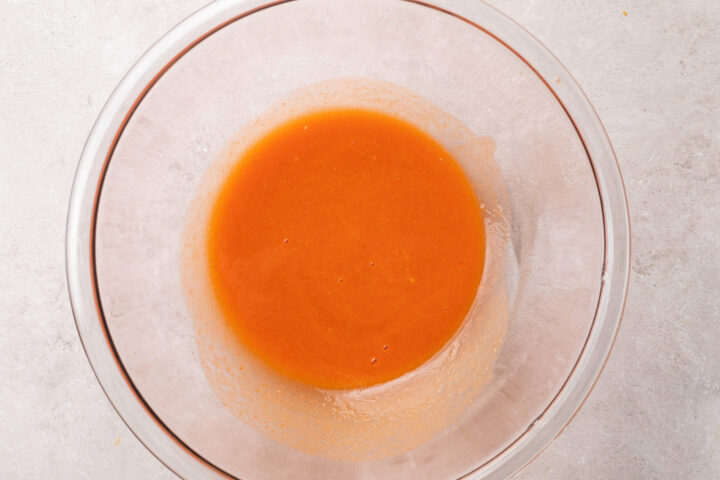 Homemade buffalo sauce in a large glass mixing bowl.