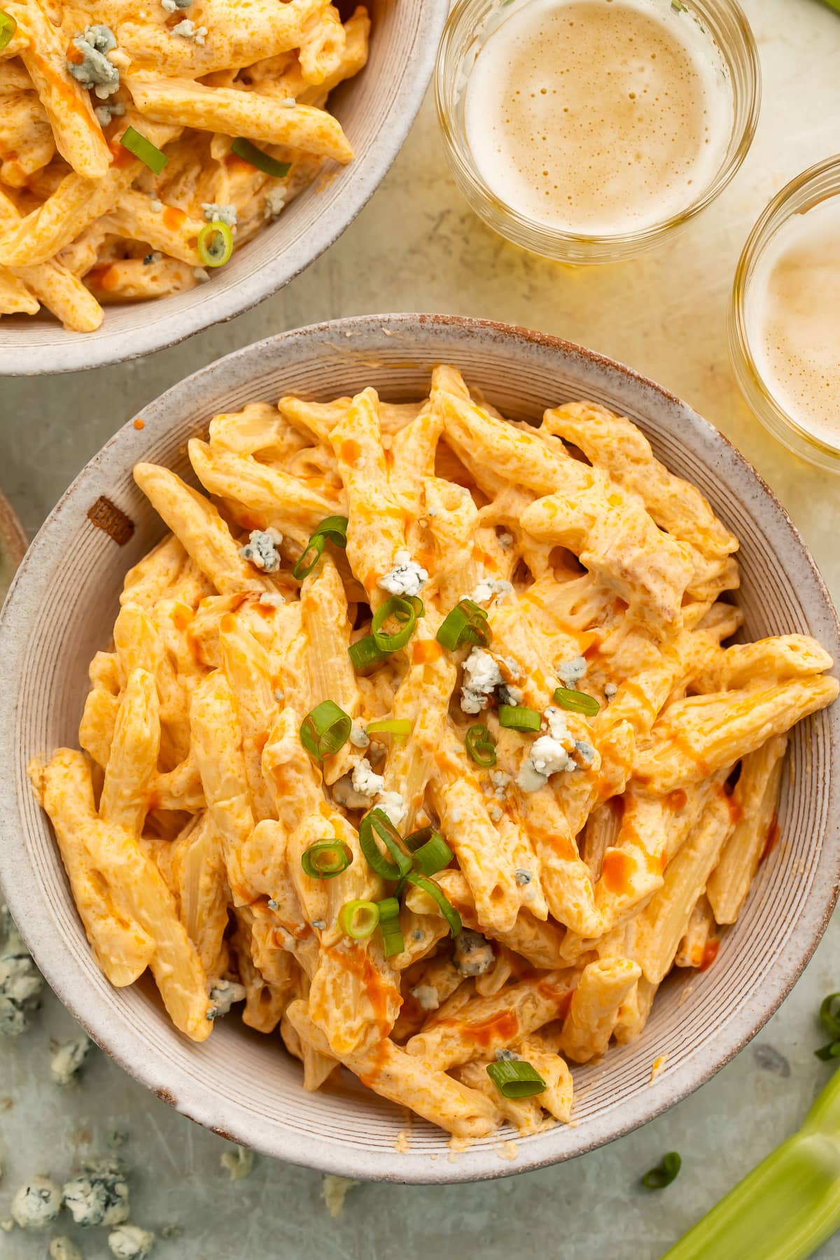 Overhead, zoomed out view of an off-white bowl of buffalo chicken alfredo made with penne pasta on a table.