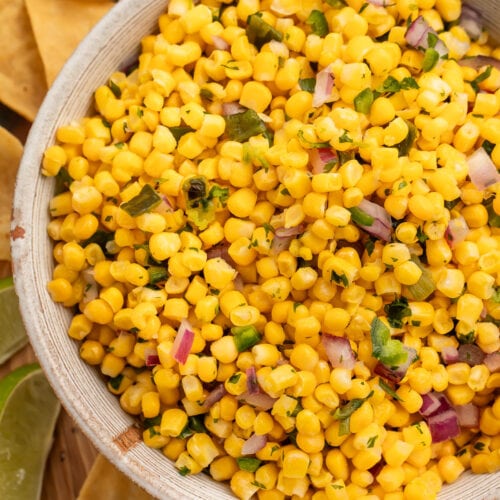 A bowl of roasted chili corn salsa surrounded by tortilla chips.