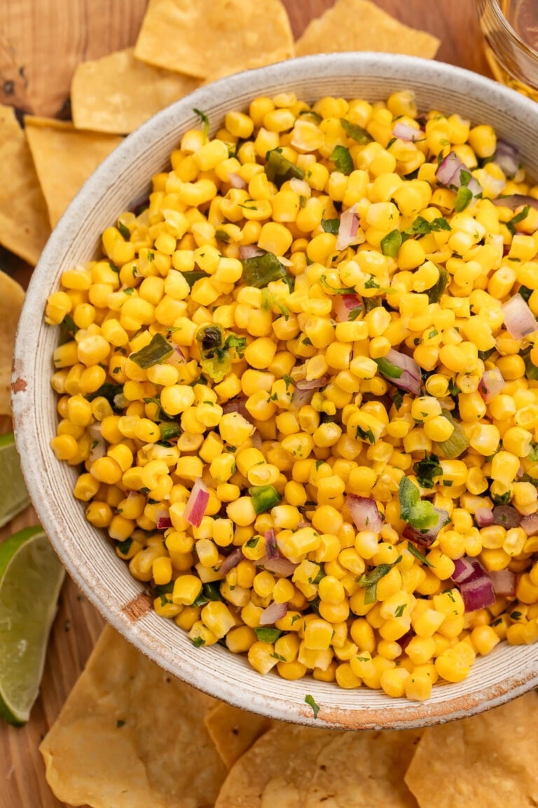 A bowl of roasted chili corn salsa surrounded by tortilla chips.