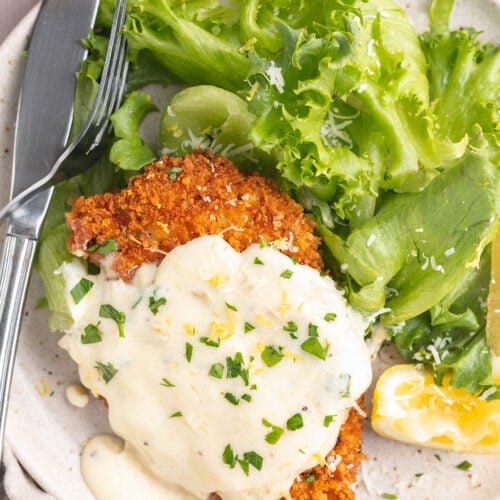 Chicken romano on a plate with a small green salad.