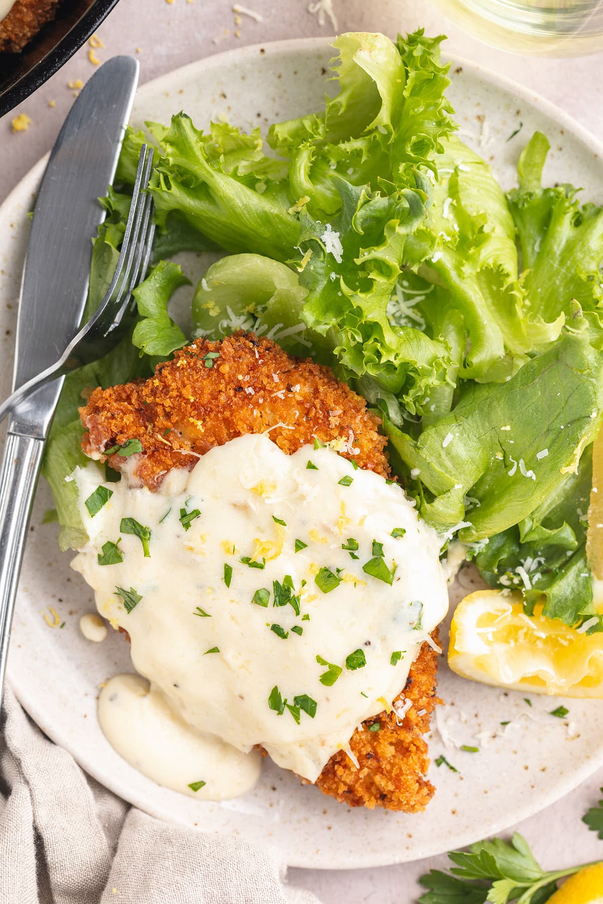 Chicken romano on a plate with a small green salad.