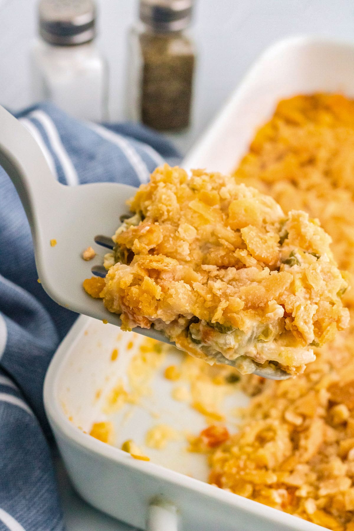 A spatula lifting a serving of veg-all casserole out of a rectangular casserole dish.