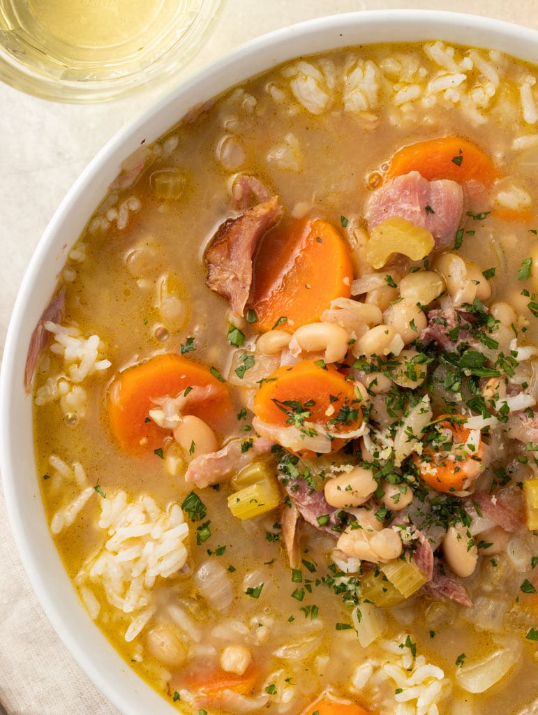 Overhead view of smoked turkey and white bean soup in a white bowl.