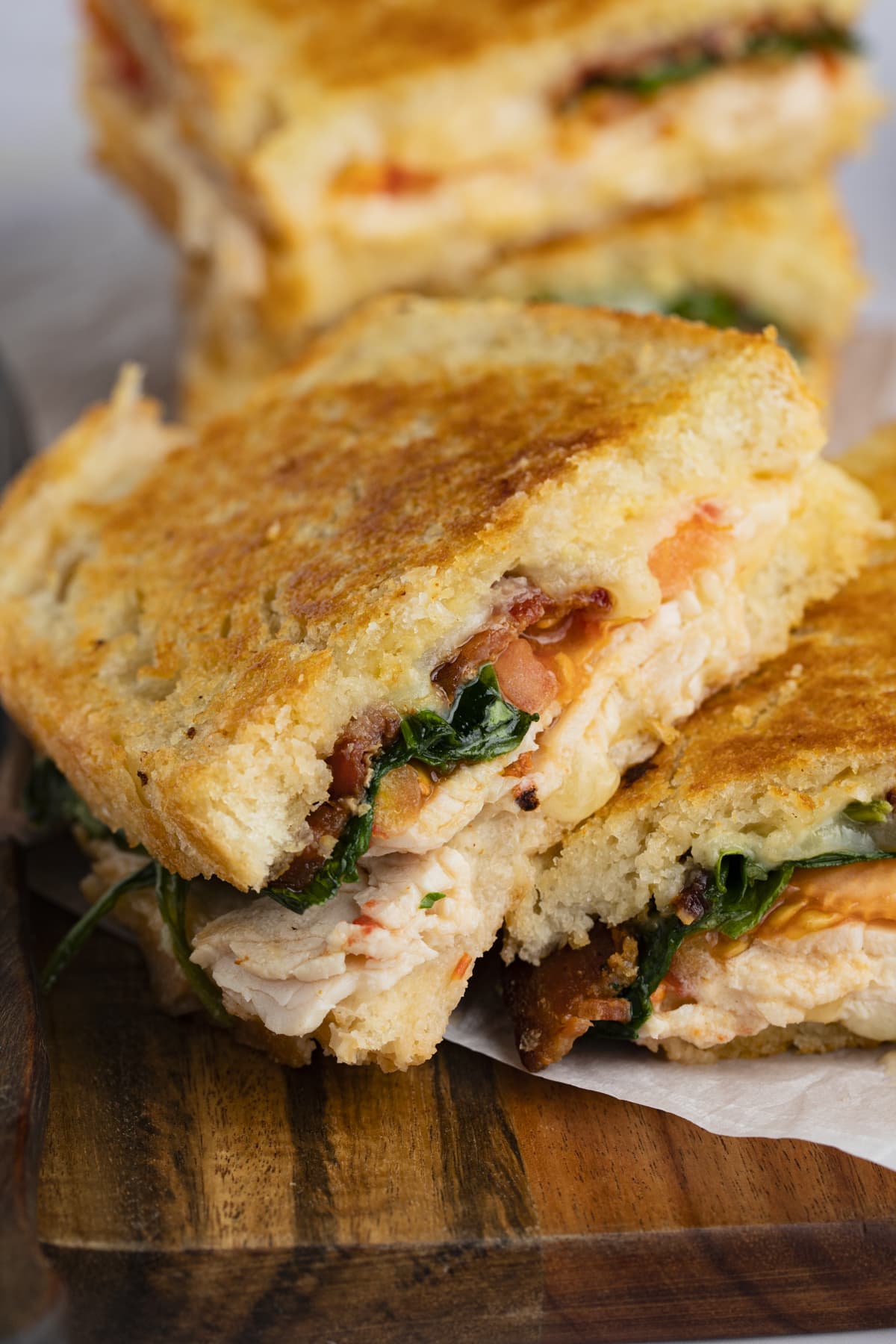 Turkey melt with spinach, bacon, and cheddar on a wooden cutting board.