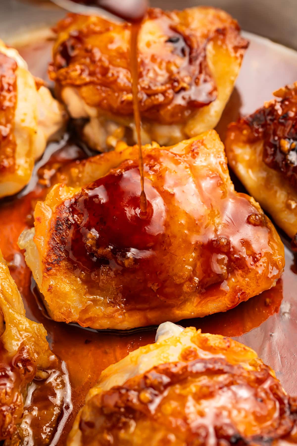 Close-up of a honey garlic chicken thigh in a skillet with honey-garlic sauce.