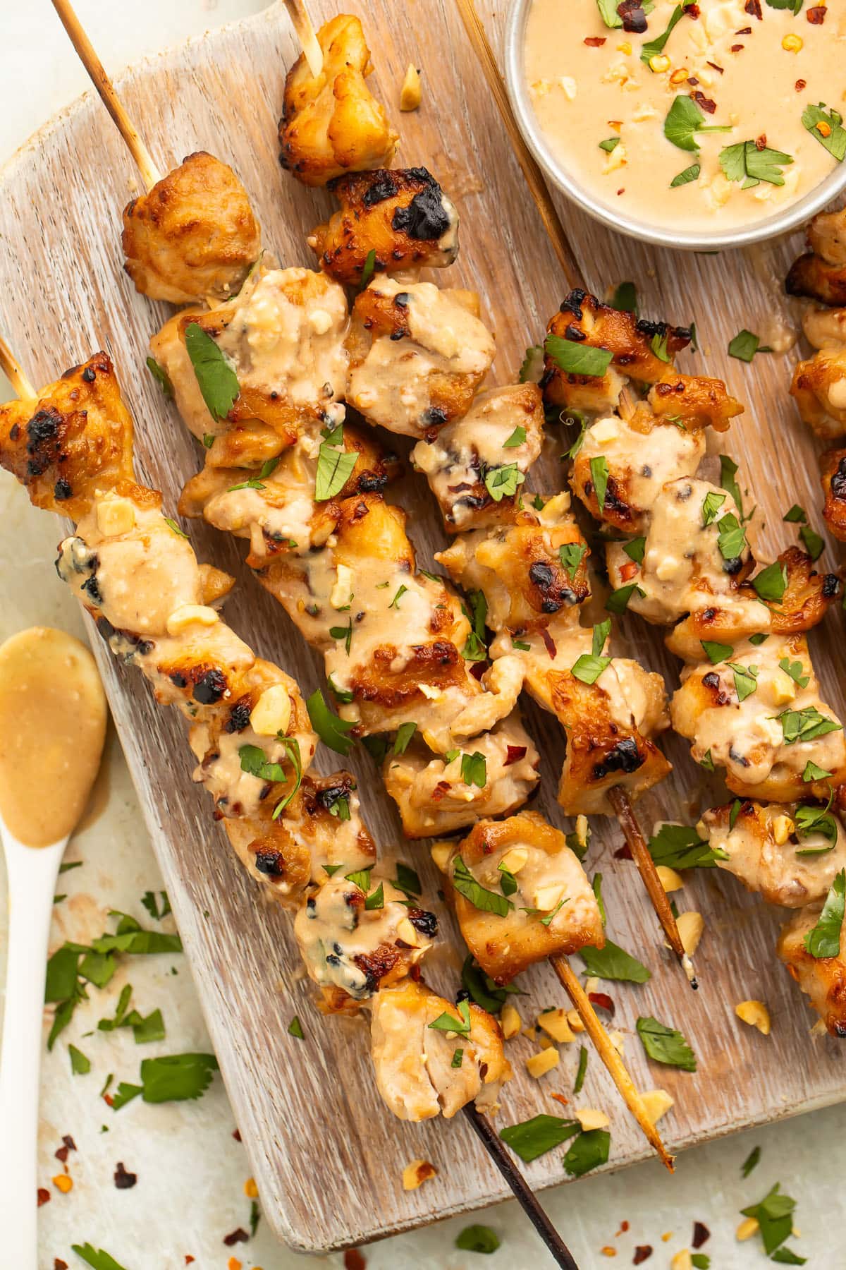 Chicken satay on bamboo skewers resting on a wooden serving board.