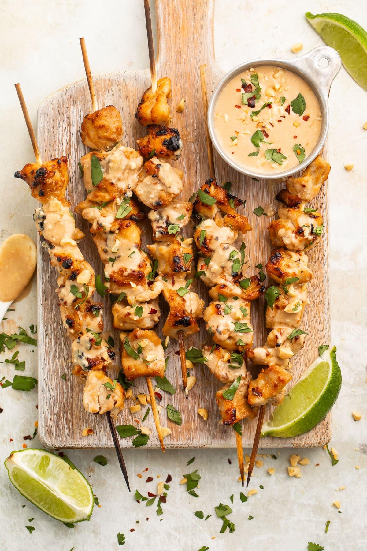 Chicken satay on bamboo skewers resting on a wooden serving board.