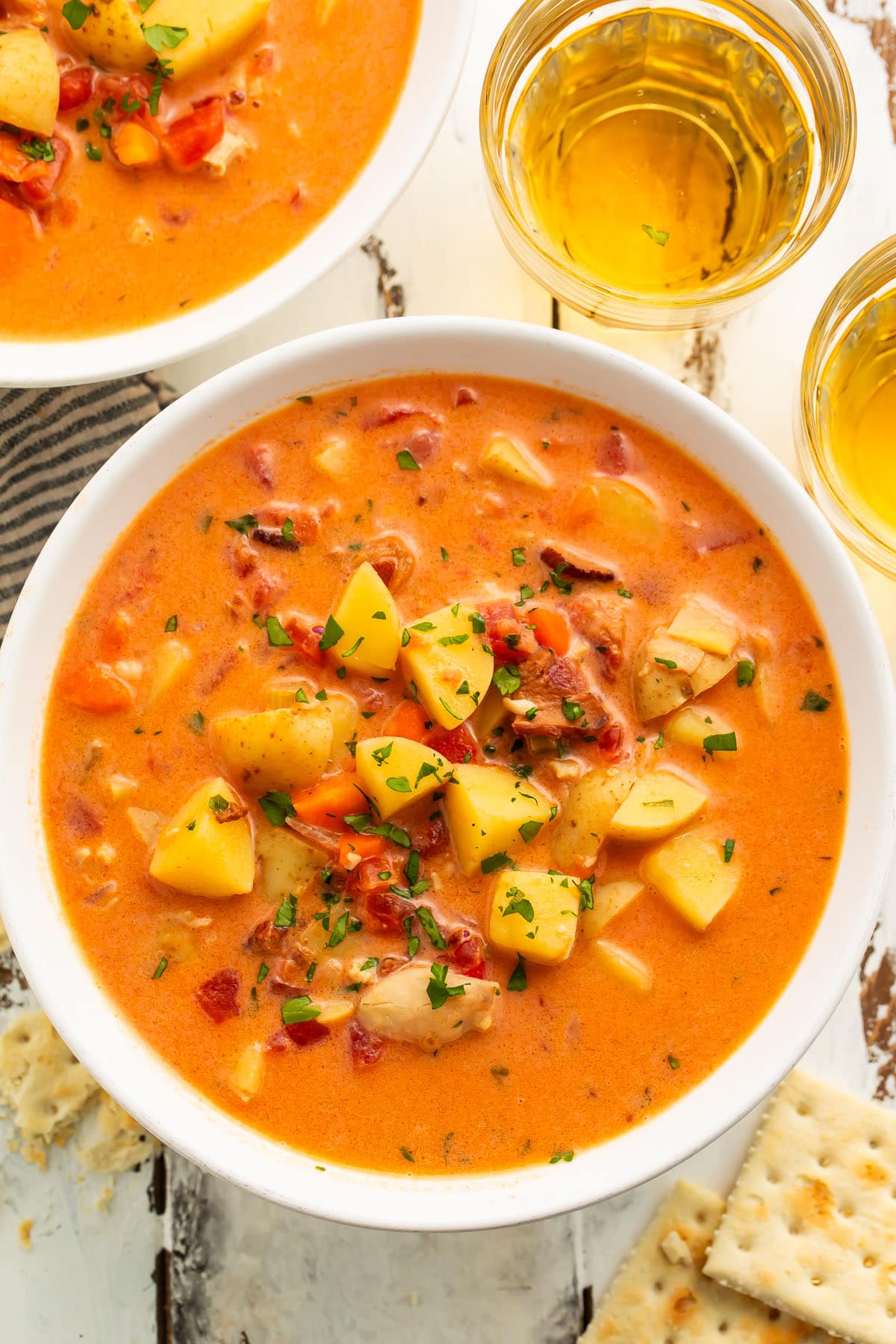 Overhead view of Manhattan clam chowder in a large white soup bowl with chunks of diced potatoes and chopped clams.