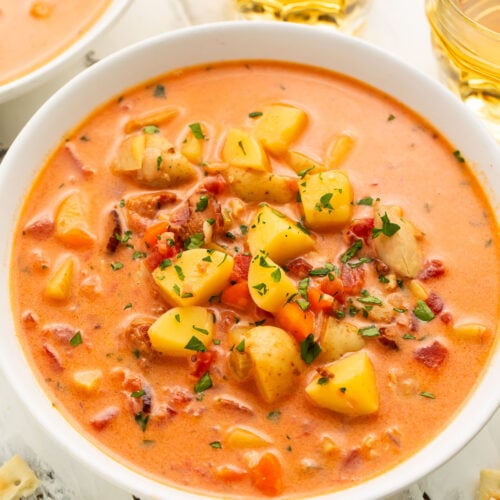 Overhead view of Manhattan clam chowder in a large white soup bowl with chunks of diced potatoes and chopped clams.