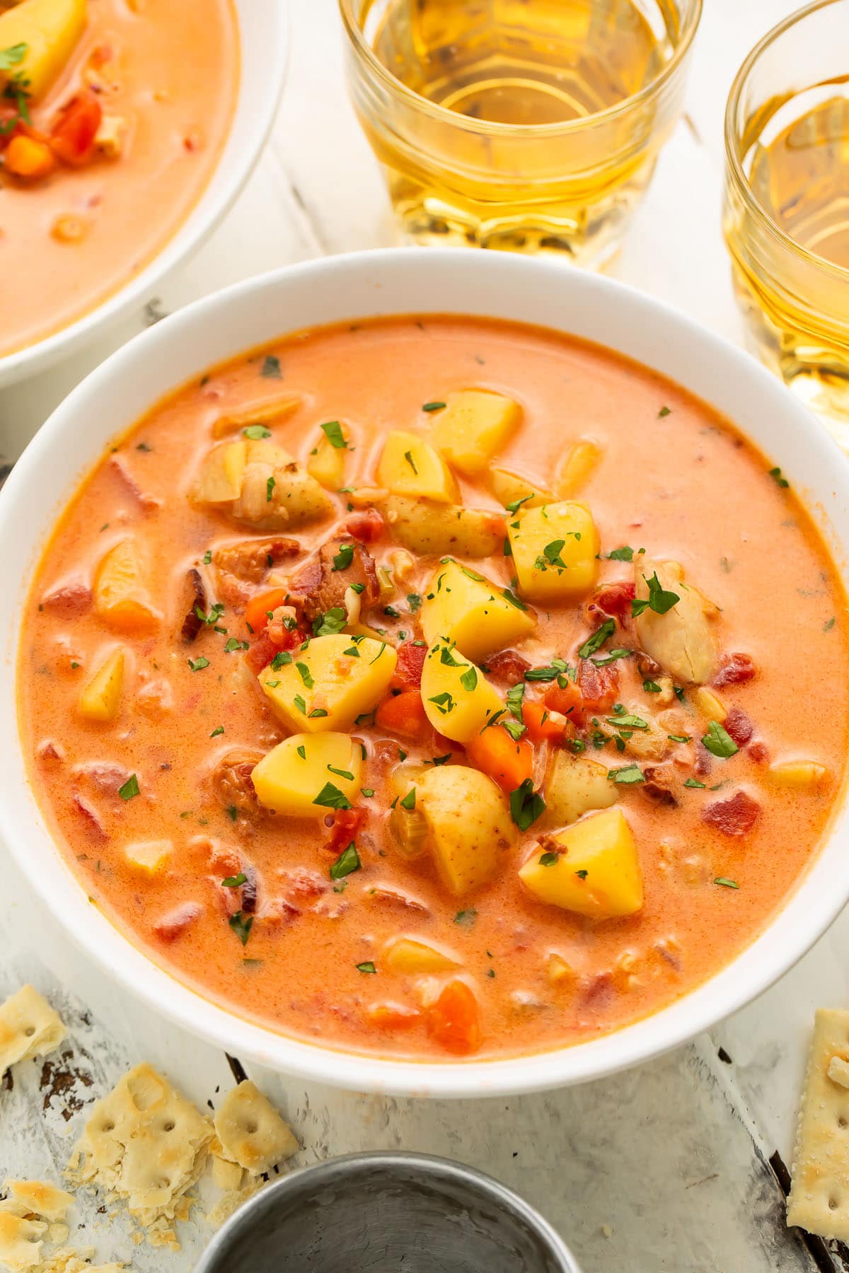 Overhead view of Manhattan clam chowder in a large white soup bowl with chunks of diced potatoes and chopped clams.