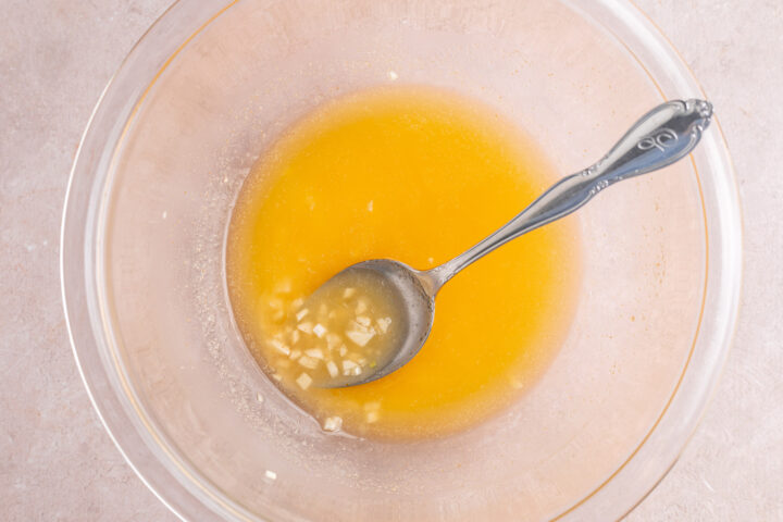 Prepared garlic butter sauce in a large glass mixing bowl with a silver spoon.