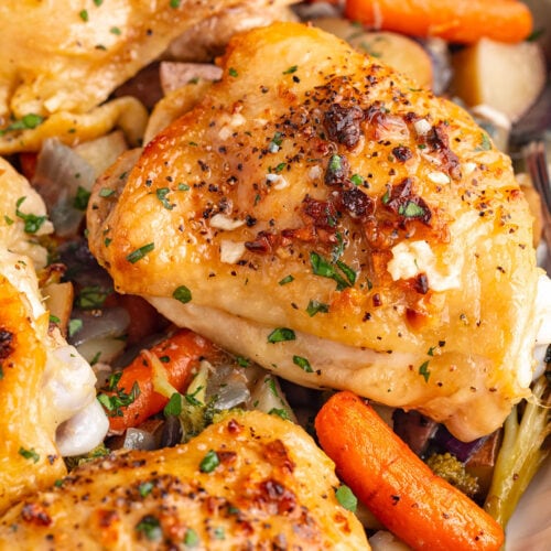 Chicken thighs and roasted vegetables on a sheet pan.