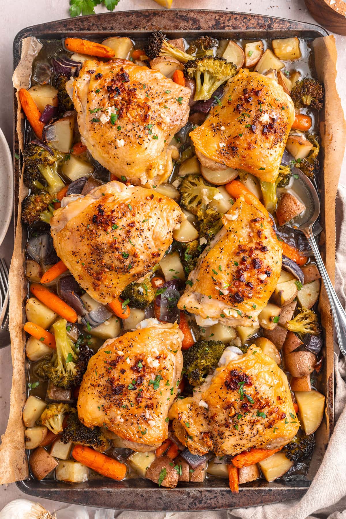 One-pan garlic butter chicken thighs and mixed veggies on a sheet pan.