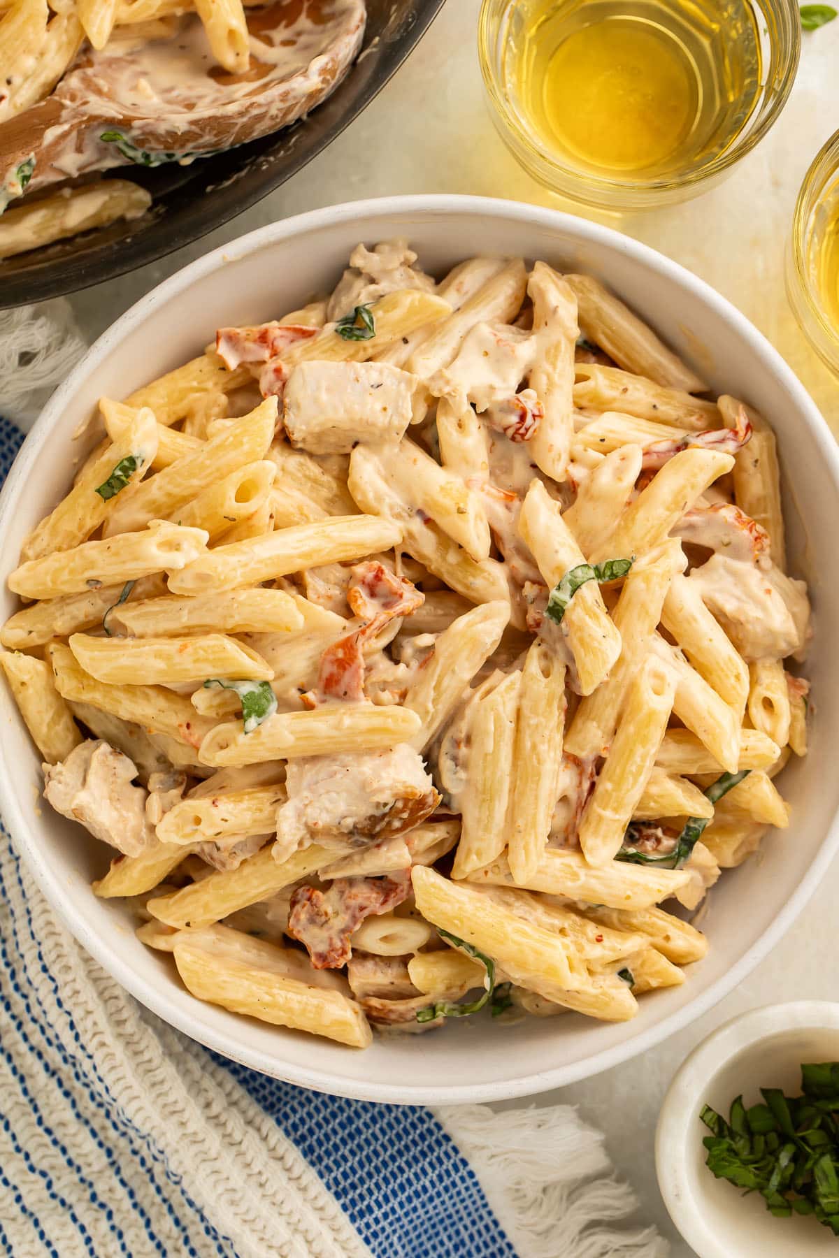 A bowl of marry me chicken pasta on a table set for dinner.