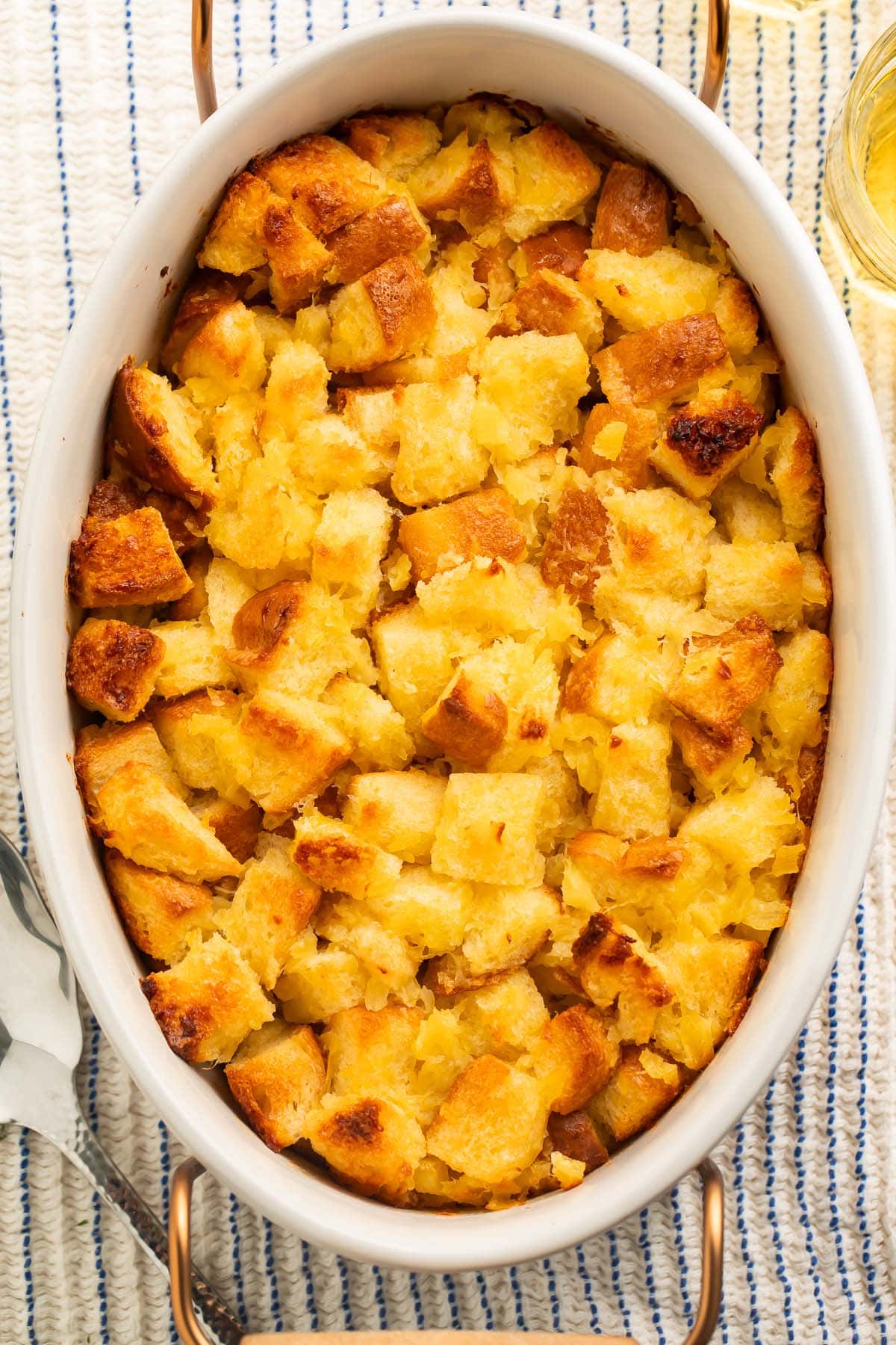 An overhead photo of pineapple stuffing in a large white oval ceramic baking dish.