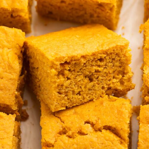 Close-up of a piece of sweet potato cornbread resting atop another piece of cornbread to better show the inside texture of the bread.